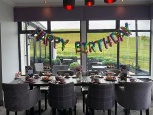 a dining room with a long table with chairs and a sign at The Knowes Hotel & Restaurant in Macduff