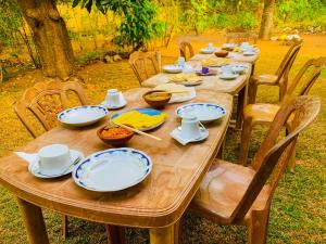 a wooden table with plates and bowls of food on it at Chill Spot Family Room and Hostel in Sigiriya +36 photos