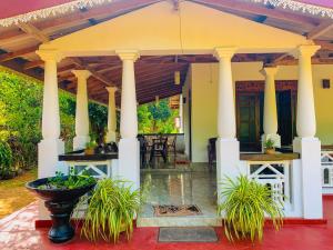 a large pavilion with columns and plants in front of a house at Chill Spot Family Room and Hostel in Sigiriya