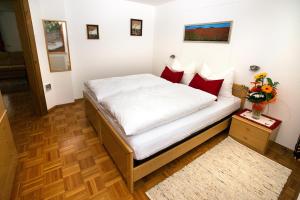 - une chambre avec un lit doté de draps blancs et d'oreillers rouges dans l'établissement Cesa Sule de Sot, à Ortisei