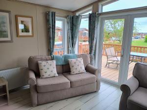 a living room with a couch and a sliding glass door at Fern Lodge with Hot Tub in Stonham Aspall
