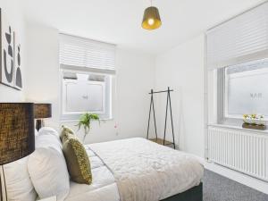een witte slaapkamer met een bed en twee ramen bij Spacious Apartment with Private Garden in Norwich