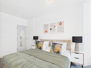 een witte slaapkamer met een bed en 2 lampen bij Spacious Apartment with Private Garden in Norwich