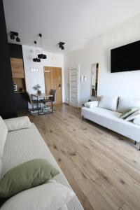 Una sala de estar con dos sofás blancos y una mesa. en Apartament LUX, en Zator