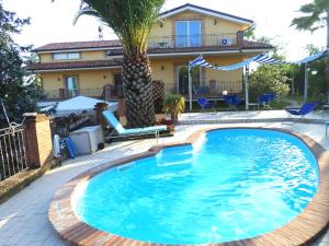 a swimming pool with a palm tree in front of a house at Bed and Breakfast Villa Algi in Corropoli