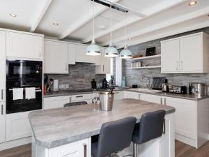 a kitchen with white cabinets and a marble counter top at Weavers Cottage in Back +10 photos