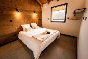 a bedroom with a large white bed with a window at Chalet authentique - Au cœur des Quatre Lacs in Le Frasnois