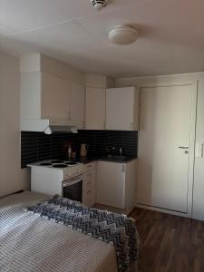 een keuken met witte kasten en een bed in een kamer bij Super central studio apartment in Tromsø