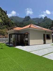 ein Haus mit einem grünen Rasen davor in der Unterkunft Refúgio da Ribeira in São Vicente