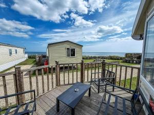 a deck with two benches and a house and the ocean at Lovely Caravan At Azure Seas Nearby The Beautiful Beach Ref 32038Az in Lowestoft