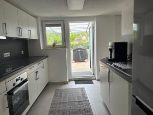 een keuken met witte kasten en een deur naar een tuin bij Unterm-Felsen in Bad Überkingen