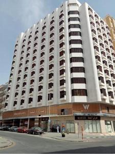 Un gran edificio blanco con coches aparcados delante. en Wedam Six Al Misfalah فندق ودام ستة, en La Meca