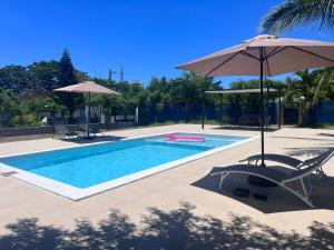 a swimming pool with an umbrella and two chairs and a table at Blue IV residence in Grand-Baie