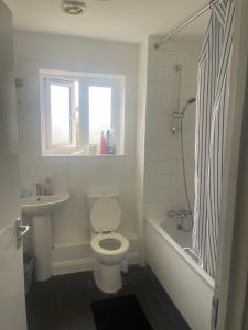 a bathroom with a toilet and a tub and a sink at ComfortVilla LR in Hornchurch