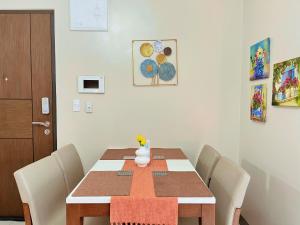 un tavolo da pranzo con sedie bianche e un tavolo di legno sidx sidx sidx di LUX BGC 1BR, Uptown Mall Connector, 5G WiFi, Pool, Ste 11 a Manila