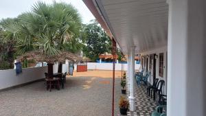 a building with chairs and a palm tree next to it at Selva Guest House in Trincomalee