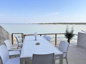 einen weißen Tisch und Stühle auf einem Balkon mit Wasser in der Unterkunft Luxus Haus direkt am Meer bei Novigrad in Dajla