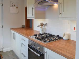 a kitchen with a stove top and white cabinets at Bramble Cottage in Craster