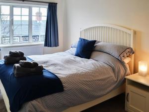 a bedroom with a bed with blue pillows and a window at Bramble Cottage in Craster +12 photos
