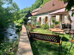 una panchina del parco accanto a un fiume con un tavolo di Au moulin maison familiale a La Broque