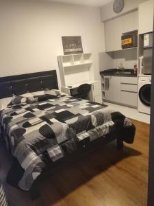a bedroom with a black and white bed and a kitchen at Hermoso Monoambiente in Cochabamba