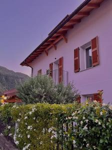 a white house with brown windows and a hedge at LoSteLaDa sul lago di Como in Colico
