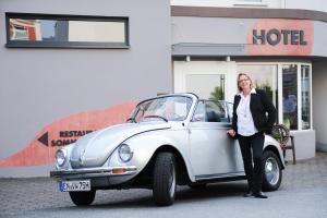 a woman is standing next to a white car at Hotel Alte Redaktion in Gevelsberg