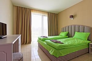 Un dormitorio con una cama con sábanas verdes y una ventana en White House, en Ognyanovo