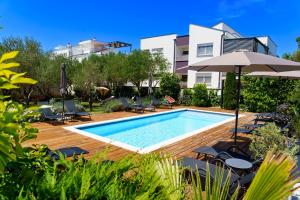 Una piscina con sillas y una sombrilla al lado de un edificio. en Villa Petar's Dream, en Privlaka