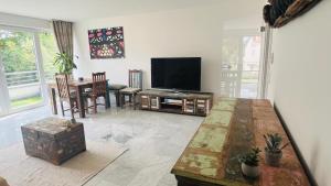 salon z telewizorem z płaskim ekranem i stołem w obiekcie Rodenkirchen Living w Kolonii