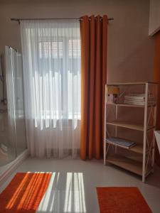 a bathroom with an orange curtain and a window at Casa Italiana with Exclusive Pool in Odesa