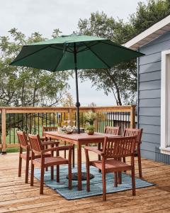WaupoosにあるGran Roble - Charming Countryside Retreatの木製テーブル(椅子付)、デッキ(パラソル付)