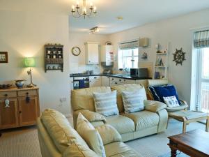 a living room with a couch and a kitchen at Captain Ron's in Beadnell