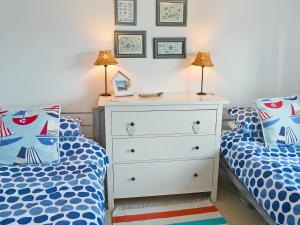 a bedroom with two twin beds and a dresser at Captain Ron's in Beadnell