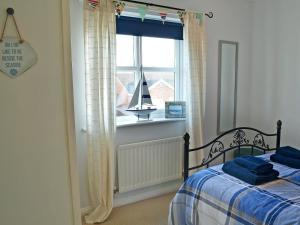 a bedroom with a bed and a window with a sailboat at Captain Ron's in Beadnell +6 photos