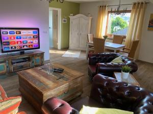 a living room with leather furniture and a flat screen tv at Paradies in der Vulkaneifel - Panorama-Blick und Wintergarten für jedes Wetter in Burgbrohl +51 photos