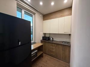 a kitchen with white cabinets and a black refrigerator at Family Comfort Apartment on Mashtots 3 in Aghk'ilisa