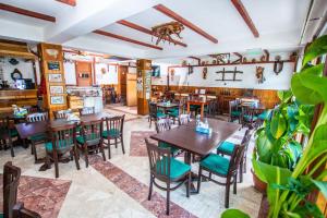 a restaurant with wooden tables and chairs and plants at Casa Albă in Baia de Aramă