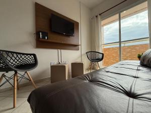 a bedroom with a bed and a flat screen tv at Pé na Areia Praia do Caiçara in Solemar +18 photos