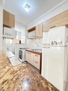 a kitchen with white appliances and a white refrigerator at Pé na Areia Praia do Caiçara in Solemar