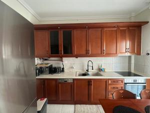 eine Küche mit Holzschränken und einer Spüle in der Unterkunft TReverie Stay -Modern 3BR Apartment for Families & Friends in Thessaloniki
