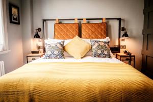 a bedroom with a large bed with yellow sheets and pillows at The Queen's Head in Kingston upon Thames