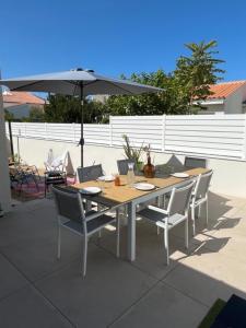 una mesa de madera con sillas y una sombrilla en el patio en Very nice house 2 steps from the beach, en La Tranche-sur-Mer