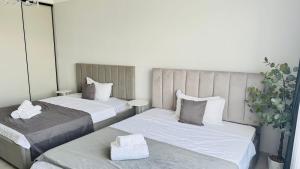 two beds in a hotel room with white sheets at 1835 Rams City Mountain View Apartment in Almaty