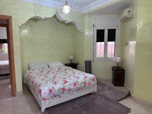 a bedroom with a bed with a floral bedspread at Élégante Villa 3 Chambres avec Jardin & Piscine Targa Afak Marrakech in Marrakech +4 photos