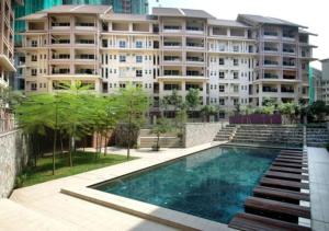 a building with a swimming pool in front of a building at Cosy place at Serimaya condo in Kuala Lumpur
