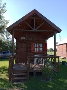a small cabin with a deck in the grass at Posada de los Gansos in Baradero