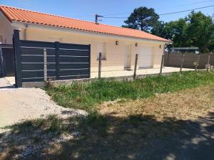 una recinzione di fronte a una casa con garage di Maison neuve Hourtin , 3 chambres, proche commodités, clôturée, climatisation, terrasse a Hourtin