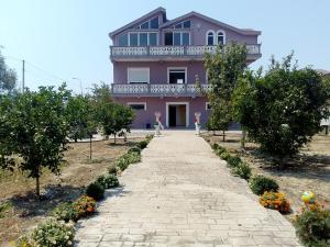 a woman standing in front of a pink house at Villas Eleni for rent best view in Xhafzotaj
