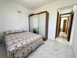 a bedroom with a bed and a mirror at Apto vista Mar c/ vaga a 200m da Praia da Mirim! in Praia Grande